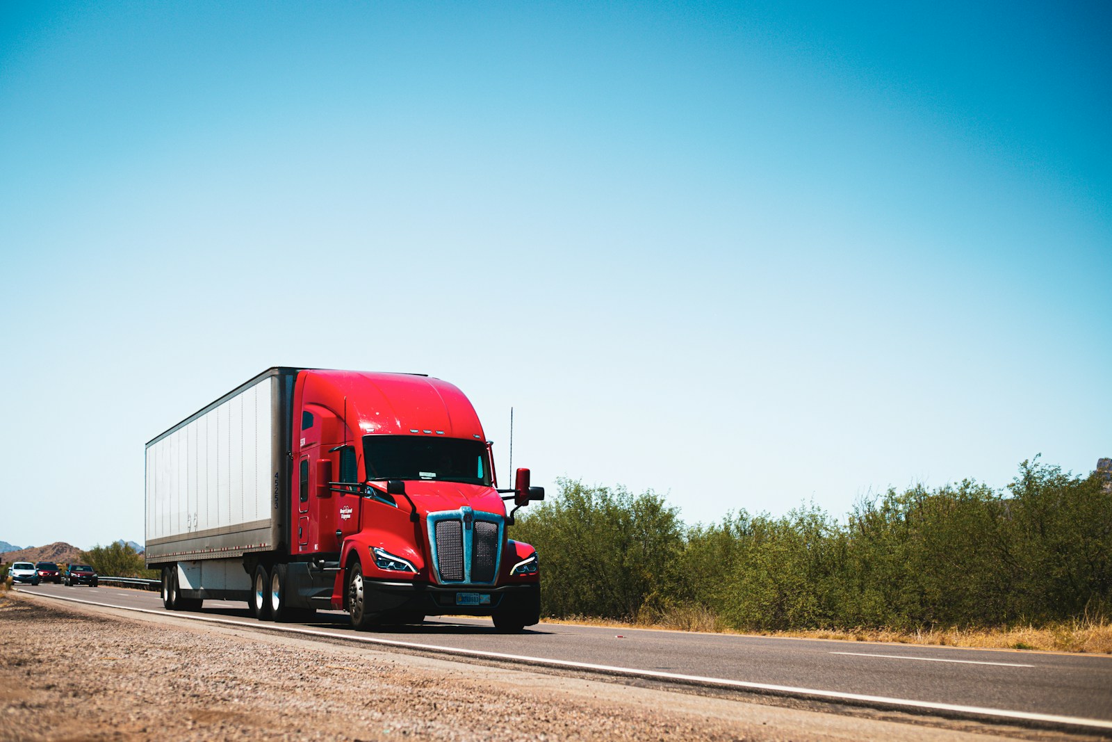 A red semi truck driving down a country road